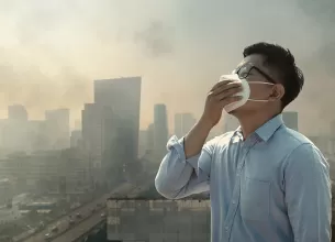 Barbat purtand masca de protectie intr-un oras afectat de poluarea PM2.5