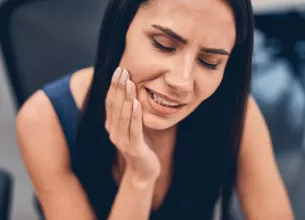 Persoana stresata care isi tine mana pe obraz, cu durere de maxilar