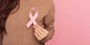 Femeie care care tine in mana o panglica roz, ca simbol al cancerului la san