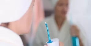Femeie pregatindu-se sa folosesca un dus bucal dupa baie