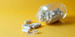 Recipient de sticla deschis cu capsule si pastile imprastiate pe suprafata