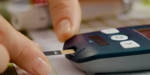 Femeie introduce cu atentie banda de test intr-un aparat pentru glicemie