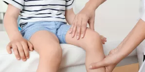 Medic care examineaza genunchiul unui copil cu probleme articulare