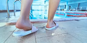 Persoana care poarta slapi la piscina pentru protectie impotriva infectiilor fungice