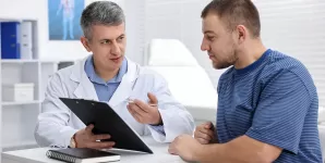 Urolog explica pacientului rezultatele consultului folosind o planseta medicala