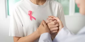 Doua femei se tin de mana oferind sprijin in lupta impotriva cancerului mamar