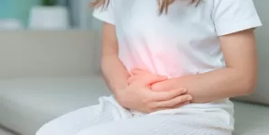 Femeie resimte dureri abdominale si isi tine stomacul din cauza disconfortului