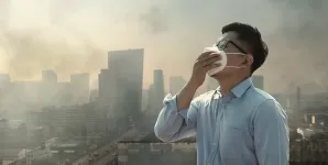 Barbat purtand masca de protectie intr-un oras afectat de poluarea PM2.5