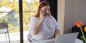 Femeie fericita lucreaza la birou folosind laptopul