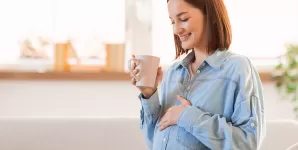 Femeie insarcinata bea o bautura calda in timpul sarcinii