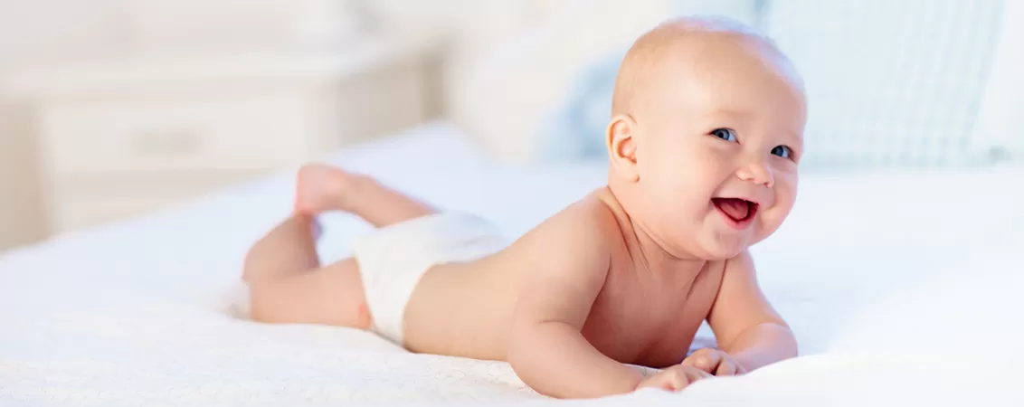 Bebelus care zambește și sta pe un pat