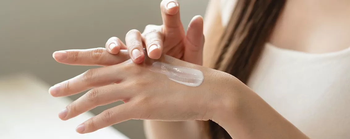 Femeie care aplica o crema pe maini pentru ingrijirea pielii