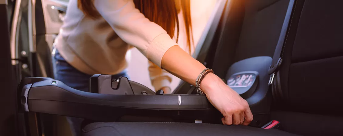 Femeie ce fixeaza in masina baza pentru scoica auto a copilului folosind isofix