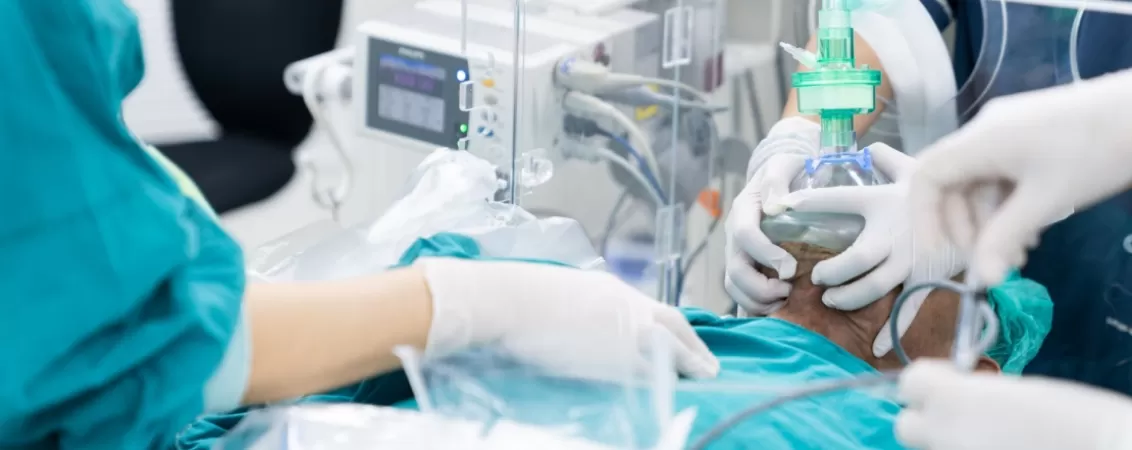 Medicul realizeaza pre-oxigenarea unui pacient sub un invelis de plastic, pregatindu-l pentru intubatie