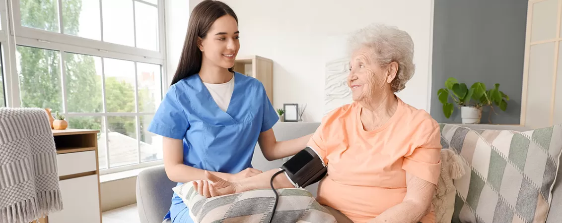Tanara asistenta care ia tensiunea unei femei in varsta