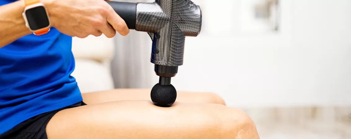 Adult isi maseaza cvadricepsul cu un pistol de masaj