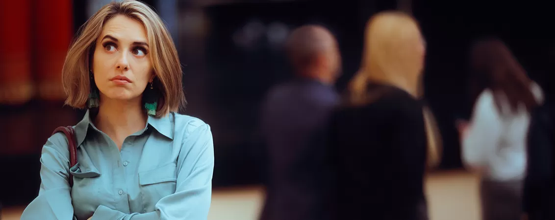 Femeie introvertita stand singura la un eveniment la care participa mai multi oameni