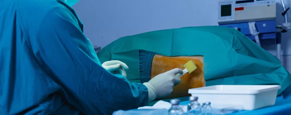 Medic in sala de operatie pregatind un pacient pentru rahianestezie