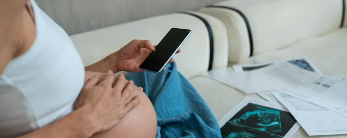 Femeie insarcinata analizeaza rezultatele testelor medicale pe o canapea