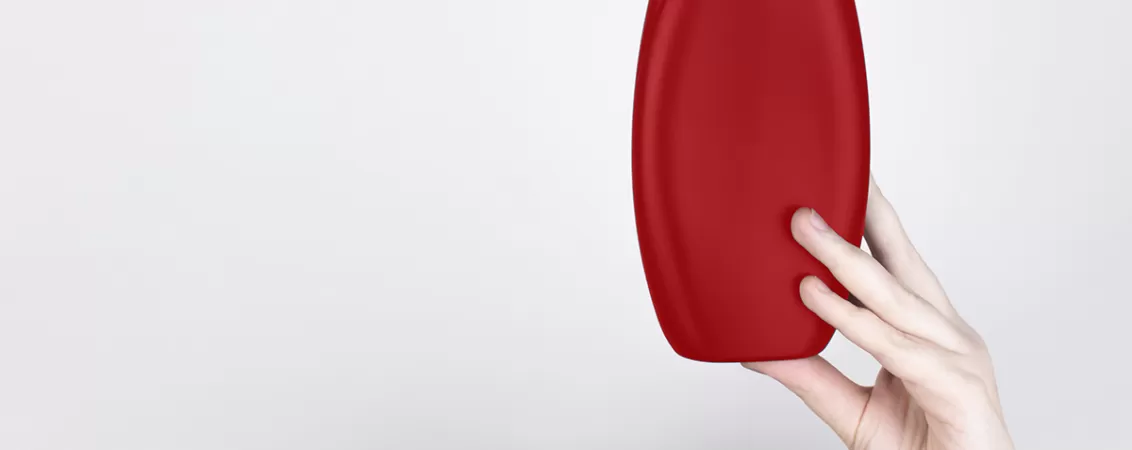 Mana tinand un recipient rosu de sampon 