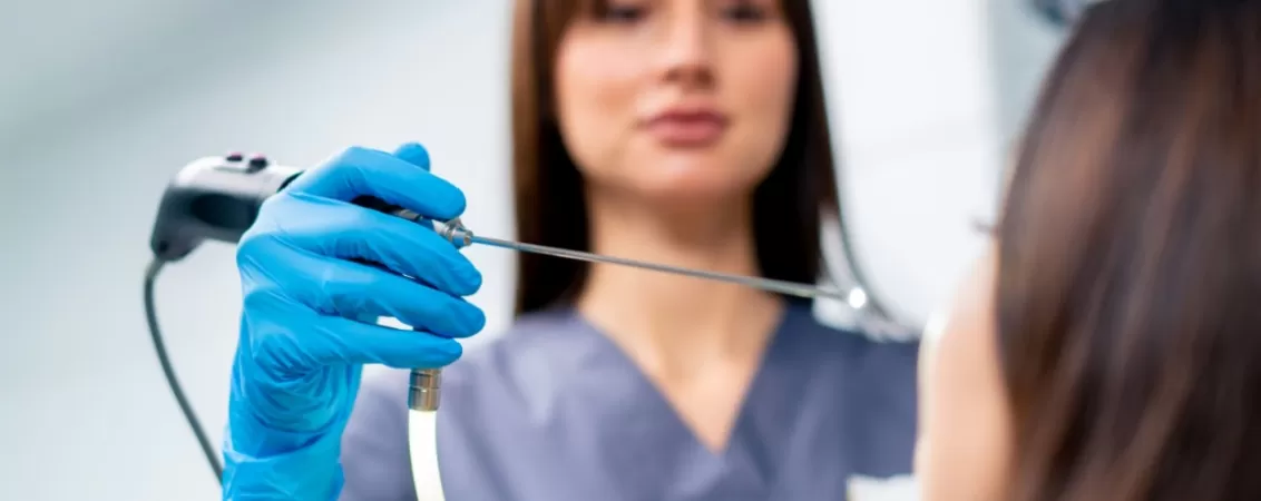 Medic ORL efectueaza o endoscopie nazala unui pacient in cabinetul medical