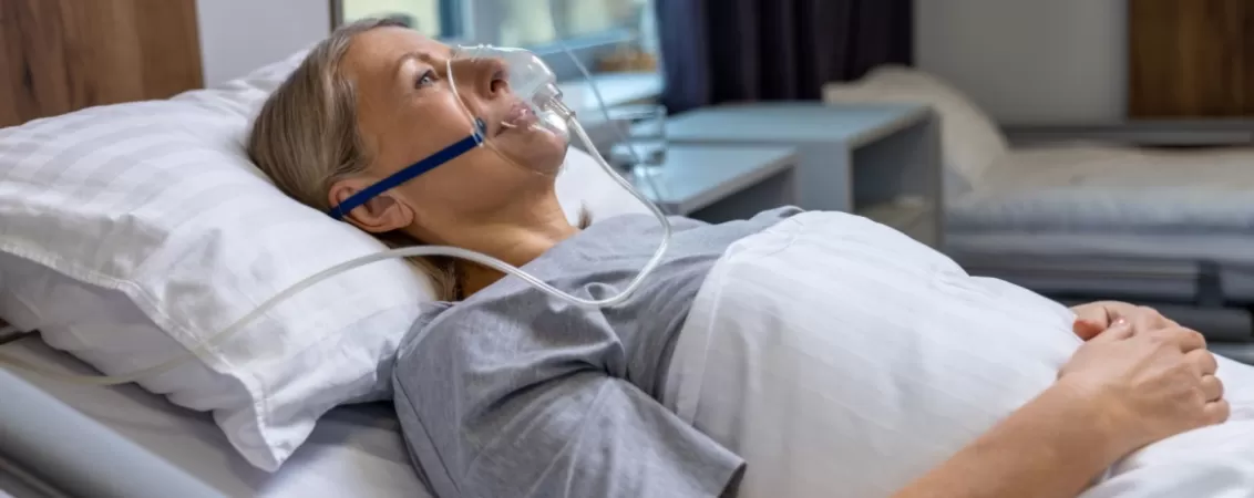Femeie pe pat de spital cu masca de oxigen