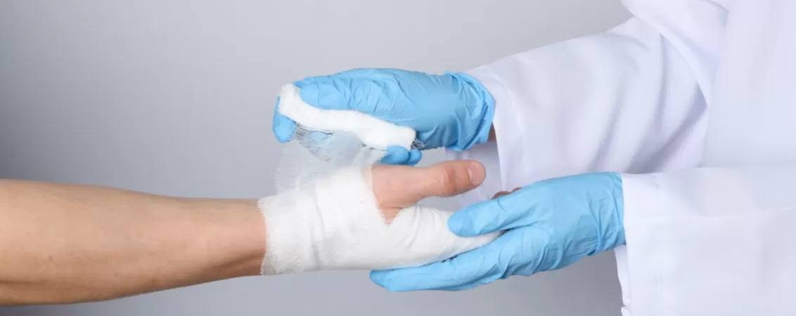 Medic aplica pansament mana