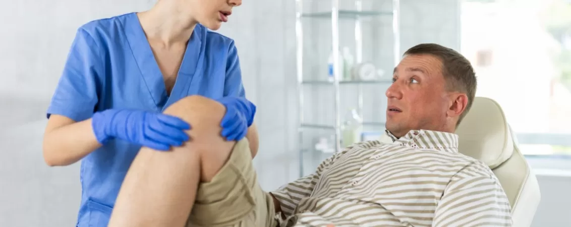 Medic evalueaza un genunchi umflat al unui pacient