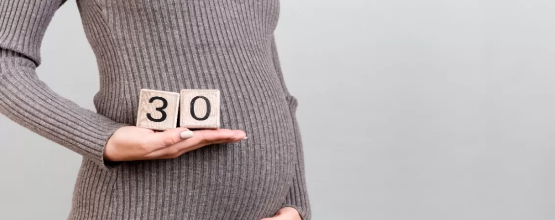 Burtica unei femei insarcinate in 30 de saptamani, cu cuburi decorative ce indica saptamana 30 de sarcina