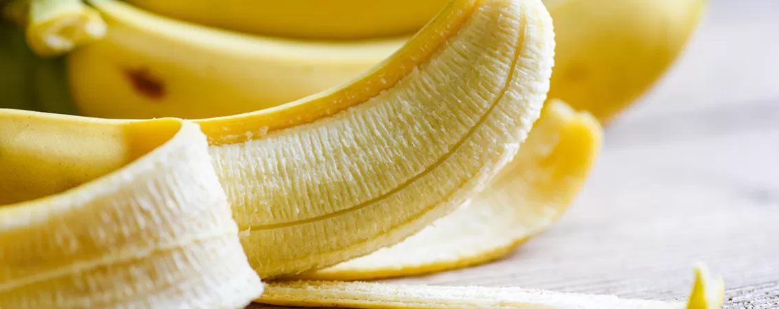 Banana partial decojita pe un fundal din lemn