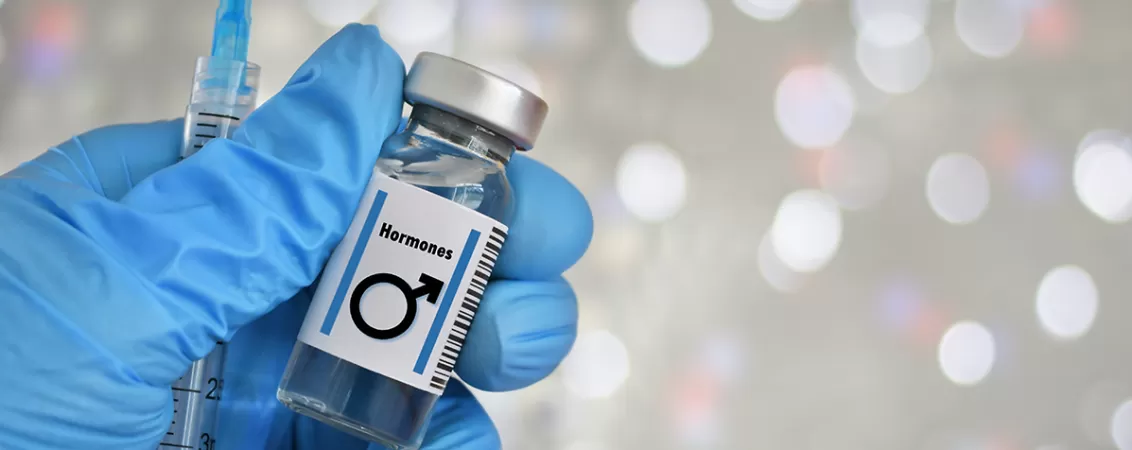 Mana cu manusa medicala tine un flacon cu simbol masculin si o seringa