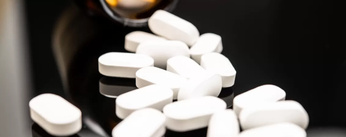 Pastile albe opioidice varsate pe o suprafata neagra – reprezentare a consumului sau abuzului de medicamente