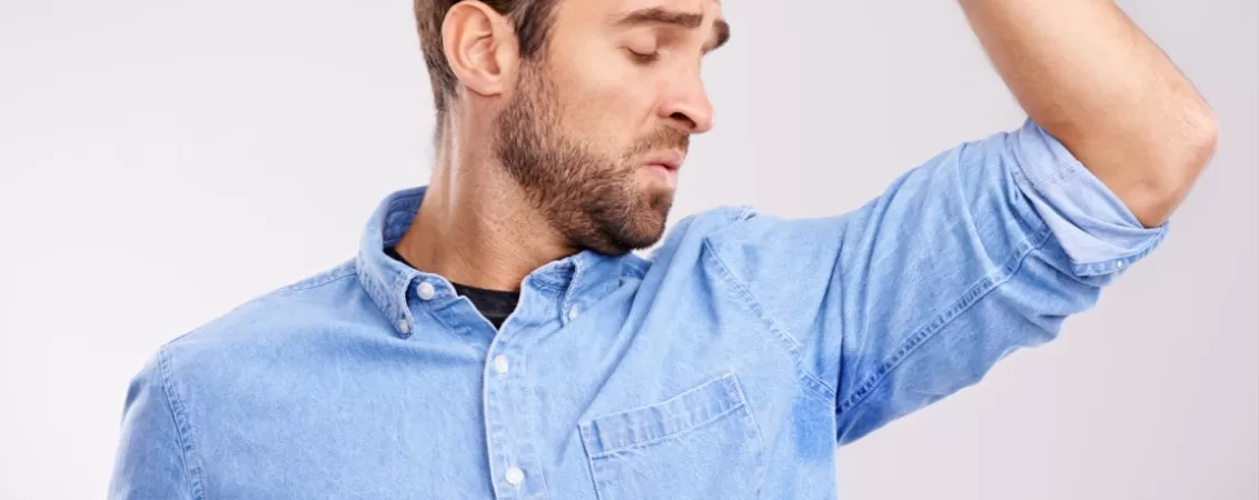 Barbat verificand pata de transpiratie de la subrat, semn de afectiune cu transpiratie excesiva