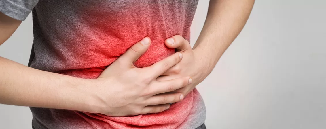 Barbat bolnav care se tine de burta, suferind de durere abdominala intensa