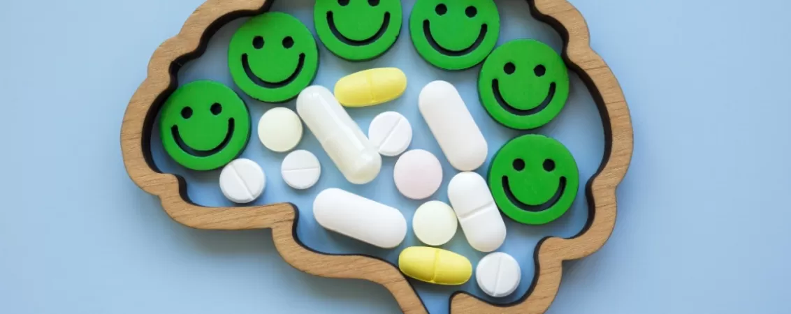Creier cu emoticoane zambitoare si pastile antidepresive, simbolizand tratamentul pentru depresie