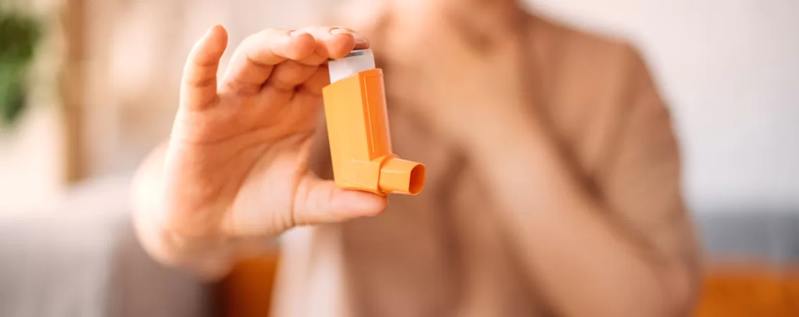 Femeie intinzand spre camera un inhalator pentru tratamentul asmului