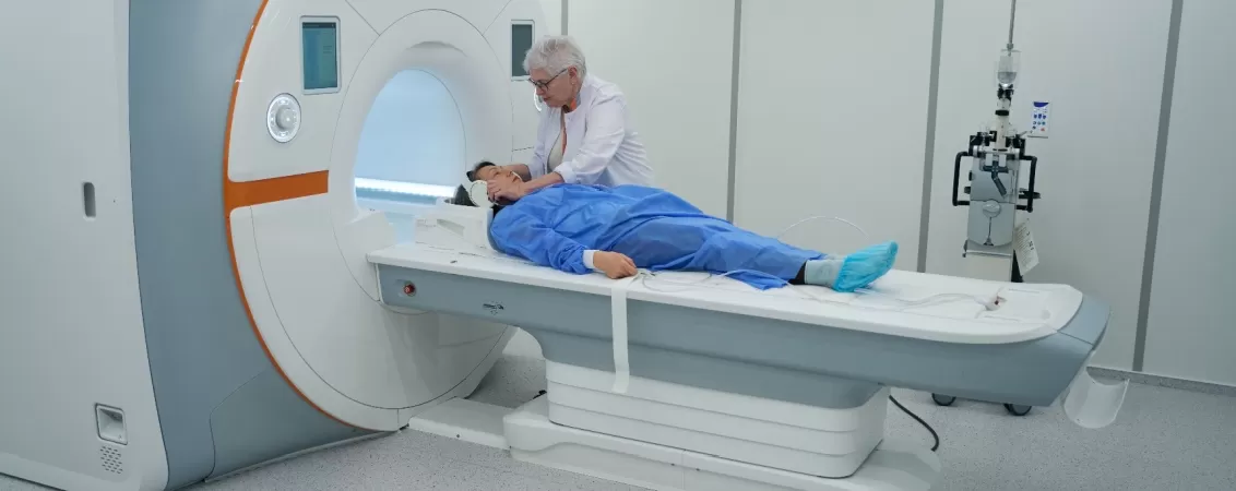 Femeie specialist in imagistica medicala care pregateste un pacient pentru o procedura de rezonanta magnetica (RMN)