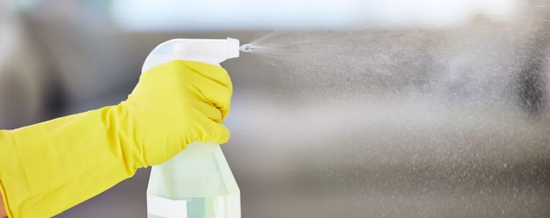 Mana cu manusa de curatenie care tine un spray cu produs antiseptic