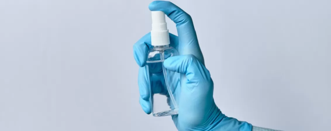 Medic in halat si manusi medicale, tinand un spray dezinfectant, pregatit pentru procedura