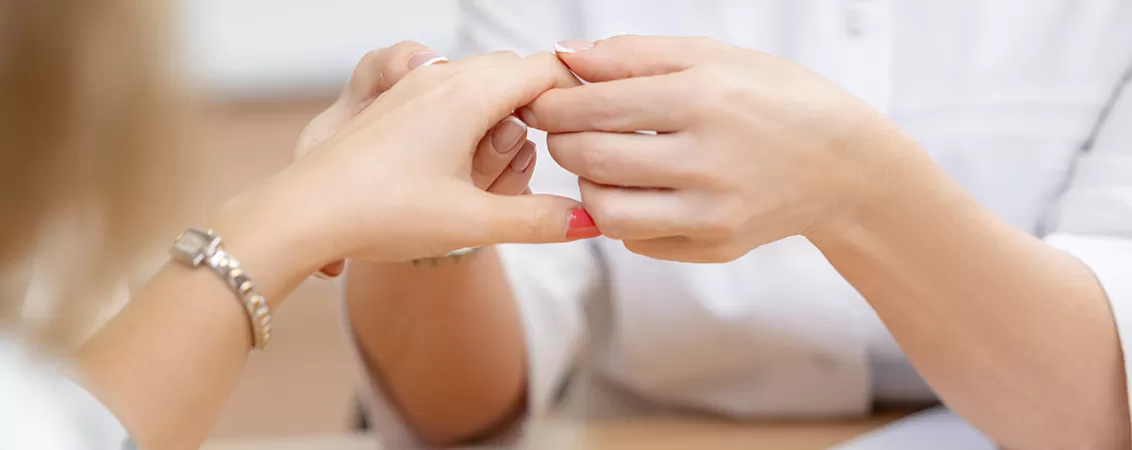 Medic reumatolog analizand mainile pacientului pentru diagnosticarea artrozei