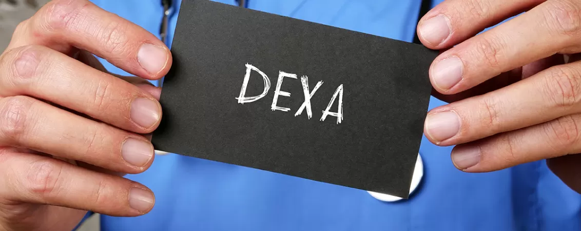 Medic tine in mana cartonas negru pe care scrie DEXA