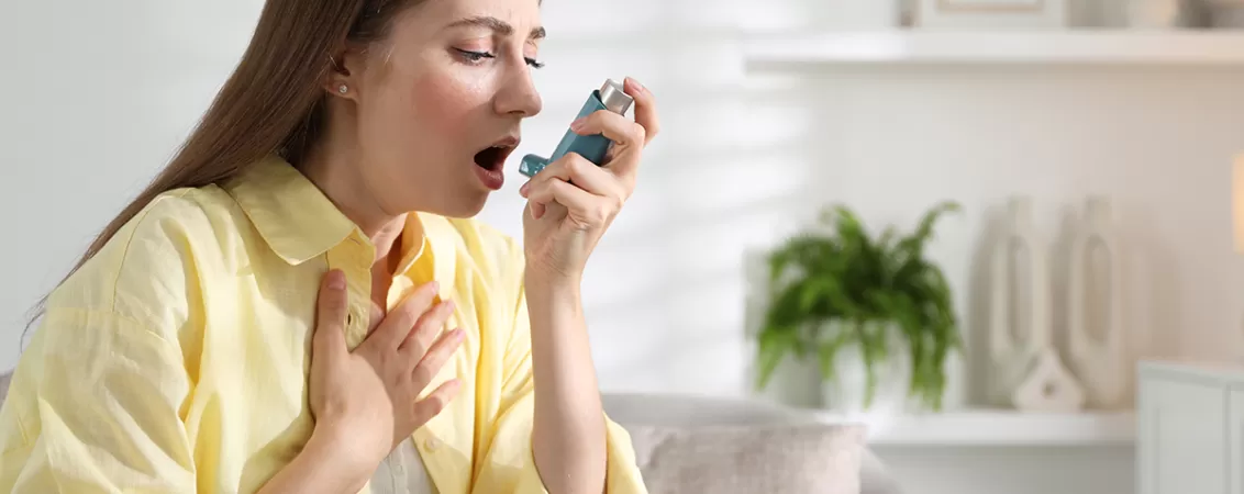 Tanara care foloseste un inhalator pentru astm acasa
