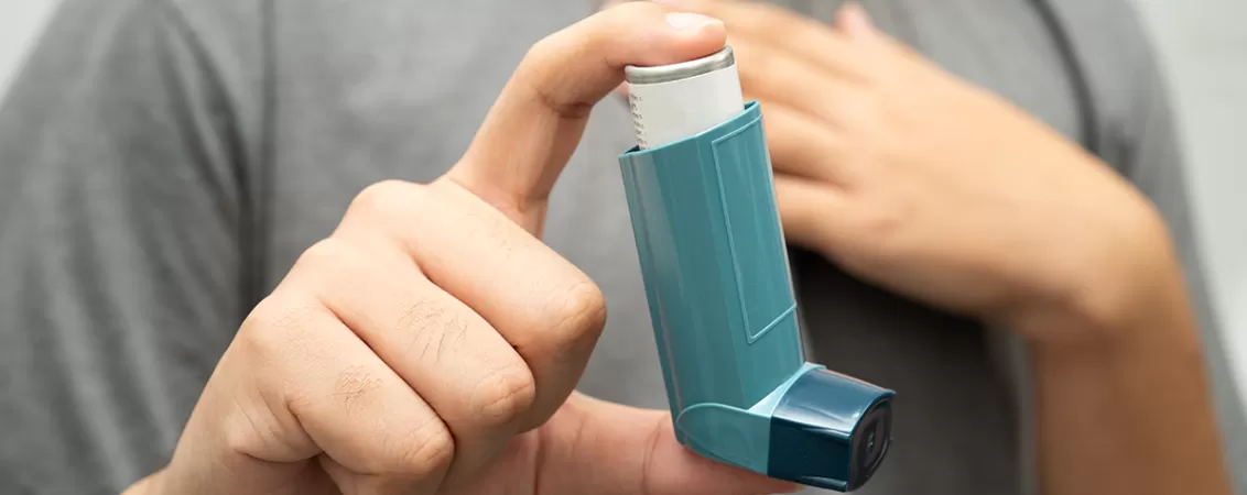 Barbat care tine in mana un inhalator MDI cu doze masurate pentru tratamentul unei afectiuni respiratorii