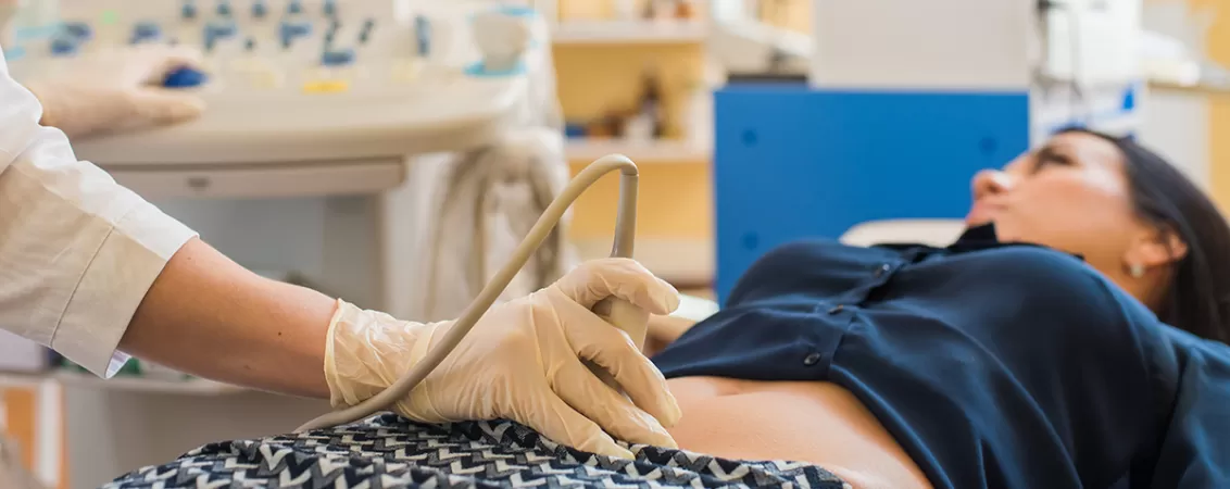 Femeie insarcinata in primul trimestru facand o ecografie in cabinetul medical