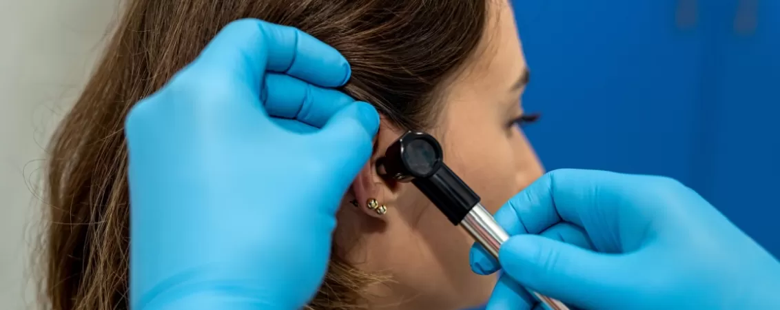 Medic ORL examinand urechea unei paciente in timpul unei consultatii