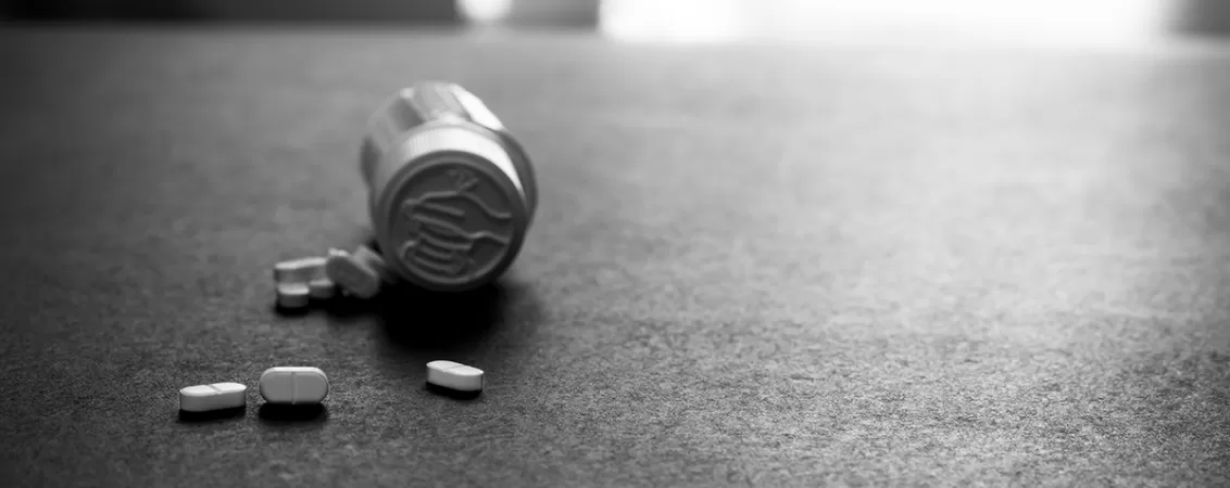 Pastile albe imprastiate langa o cutie de plastic pentru medicamente, concept de tratament si farmacologie