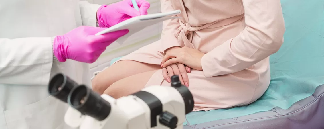 Tanara pacienta imbracata in halat medical la cabinetul ginecologic in timpul unei consultatii de rutina