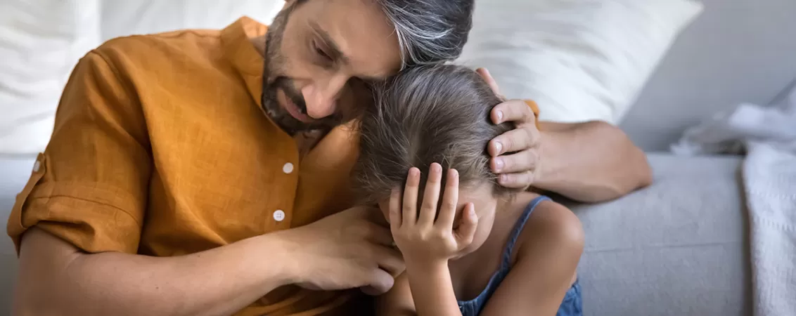 Tata indurerat care isi imbratiseaza copilul trist, concept de doliu si sprijin emotional in familie