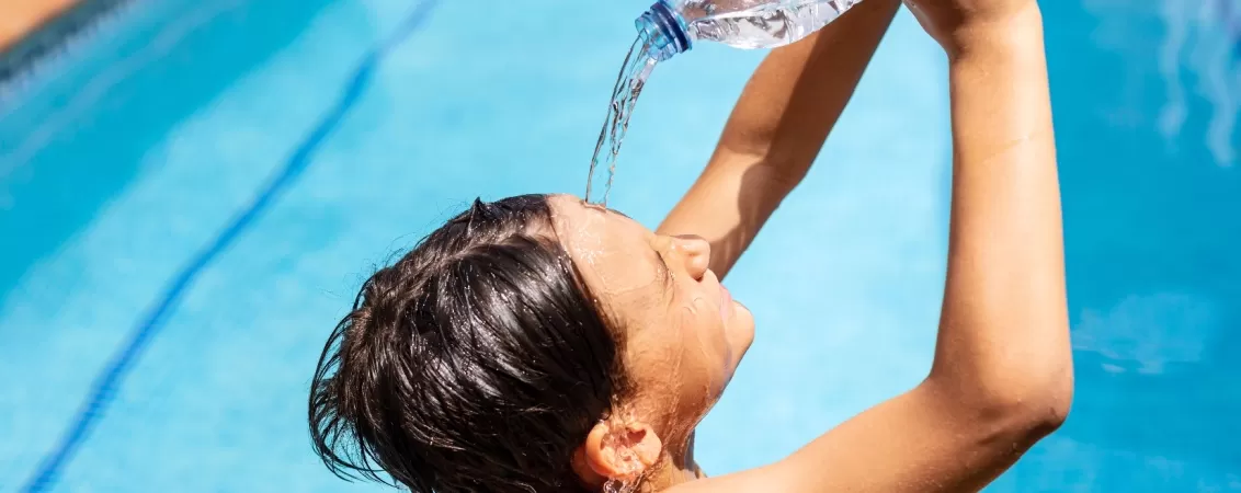 Copil care se joaca cu apa din piscina 