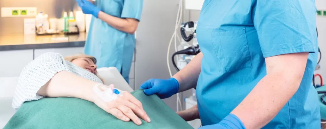 Echipa medicala pregatind o pacienta pentru o colonoscopie cu sedare